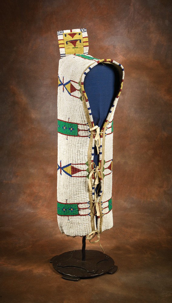 Sioux Beaded Cradle: 27” x 10” red, green, yellow and blue on a white field with geometric designs. 5” x 4 1/2” flap at the head. On native tanned hide, mounted on custom metal stand. Fine condition, c 1880. Stand