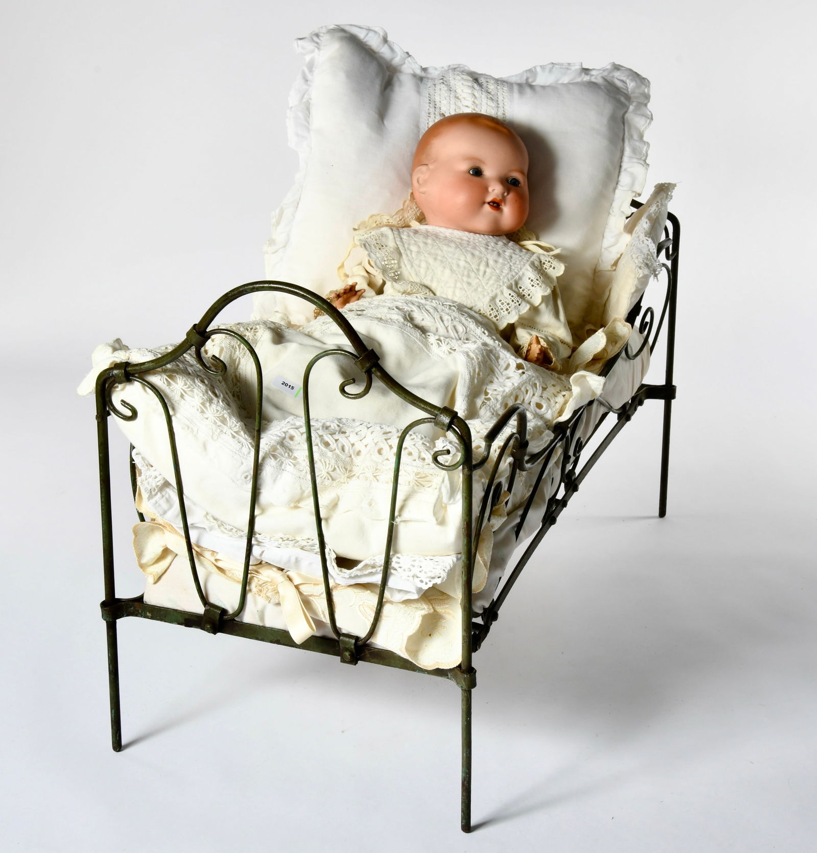 Armand Marseille, Sitz-Baby in Tagesbett: Armand Marseille, Baby doll (bisque head loose (marked A.M. Germany. 351./ 5.), eyes fixed open, mouth open, 2 teeth, fabric body with celluloid hands, slightly damaged and dirty, in metal bed, 62 x 2