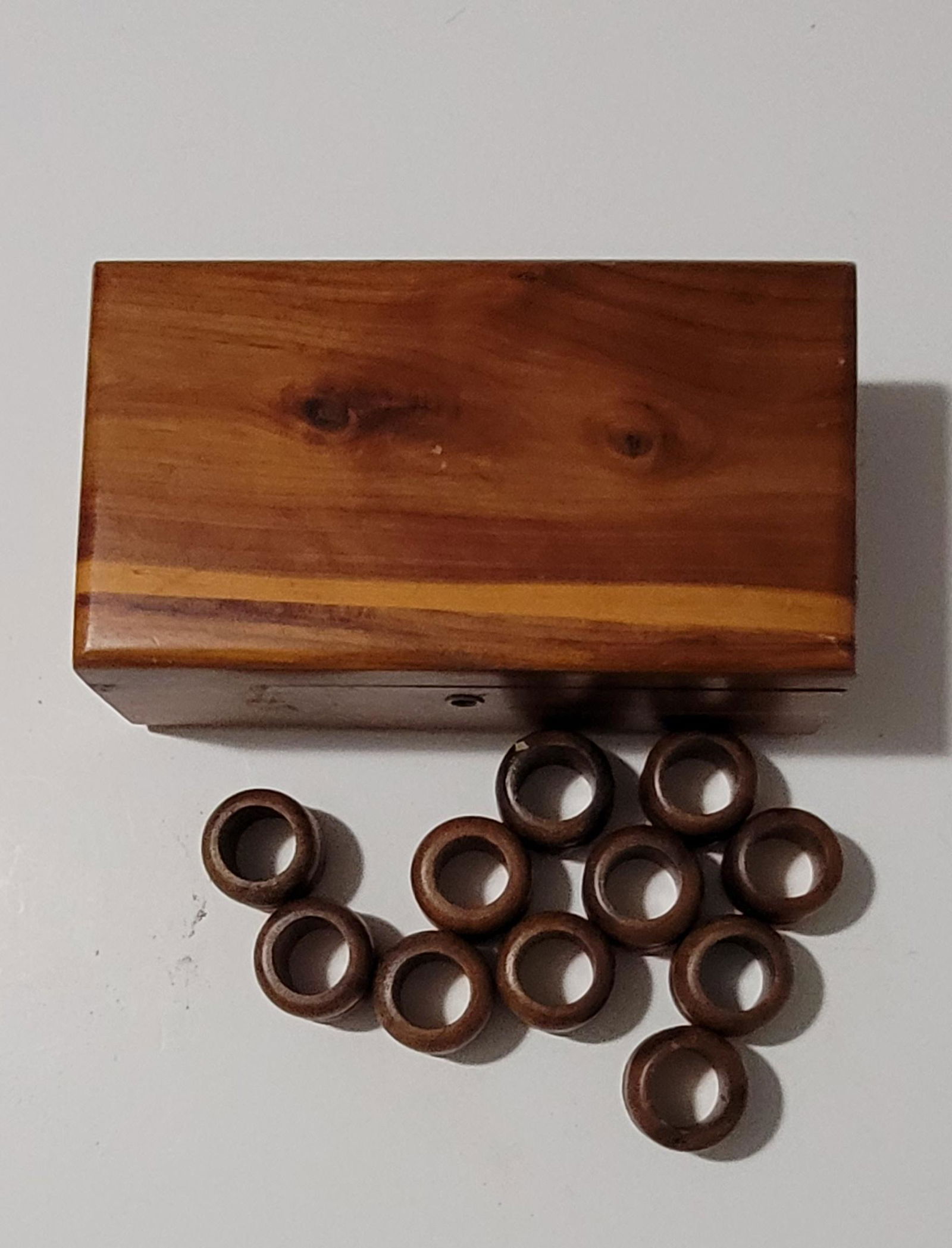 Wooden box with 11 wood napkin rings: Wooden box with 11 wood napkin rings. Box size 9x5x3.25”. Ring diameter 1.5" each.