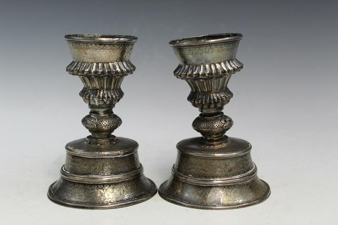 Pair of Tibetan silver candle holders.: Pair of Tibetan silver candle holders. H 13 cm.