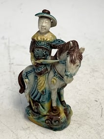 Small pottery figure of a man riding on a horse.