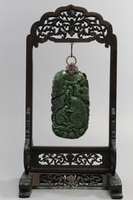 Chinese Carved Green Stone Pendant with Silver Bail on Carved Wood Stand.