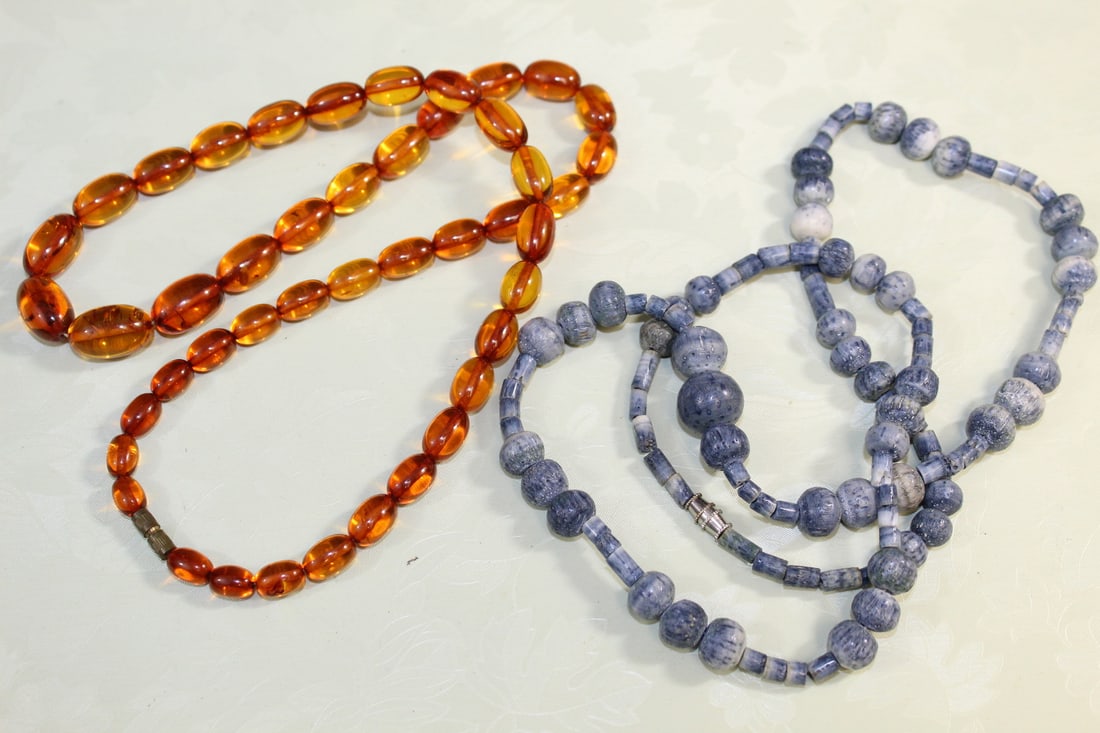 One Amber and one Dyed Coral Necklaces: One Amber and one Dyed Coral Necklaces. Amber necklace length 60 cm. Bead length 1.5 cm. Coral necklace length 70 cm.