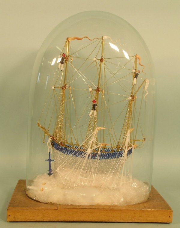 A Stourbridge glass ship group, 20th century, the: A Stourbridge glass ship group, 20th century, the spun glass sailing ship in blue, amber and clear glass modelled with three sailors, and two further smaller boats on a choppy sea, all under a glazed