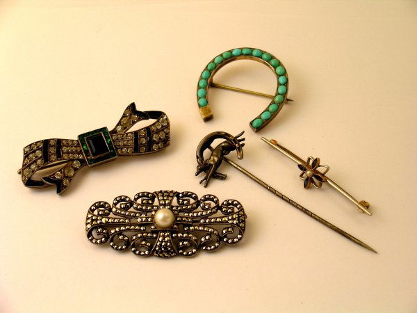 A selection of jewellery to include; a sapphire and: A selection of jewellery to include; a sapphire and seed pearl set bar brooch (a/f) a stickpin designed as a hound jumping through a horseshoe, a turquoise set horseshoe brooch stamped "AV", a green,