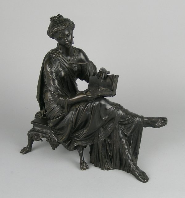 A patinated bronze figure of a young woman sat rea