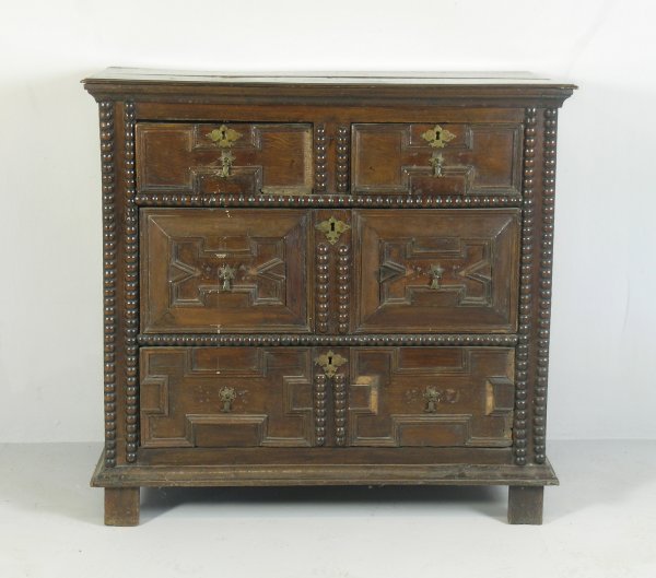 A Charles II joined chest, oak, the rectangular b: A Charles II joined chest, oak, the rectangular boarded top over two short and two long geometrically moulded drawer fronts fitted with later brass drop handles and key escutcheons, along with later s