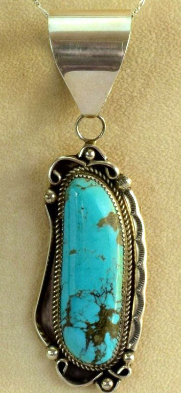 Navajo Sterling Silver Kingman Turquoise Pendant: Measures 4.25 inches in length and is 1.25 inches wide. Has a Kingman Turquoise Center stone that is 2 1/8 inches long. The piece has a large bale and is marked Sterling on the back and Hallmarked "LN