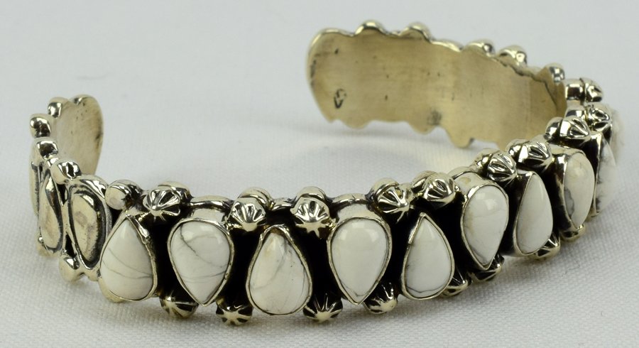 White Buffalo Turquoise Bracelet by Marcella James: Measures 1/2 inch wide with Natural White Buffalo Turquoise Stones across the top in a tear drop shape. The inside measures 5.5 inches with a gap of 1.25 inches. Marked Sterling and signed "Marcella J