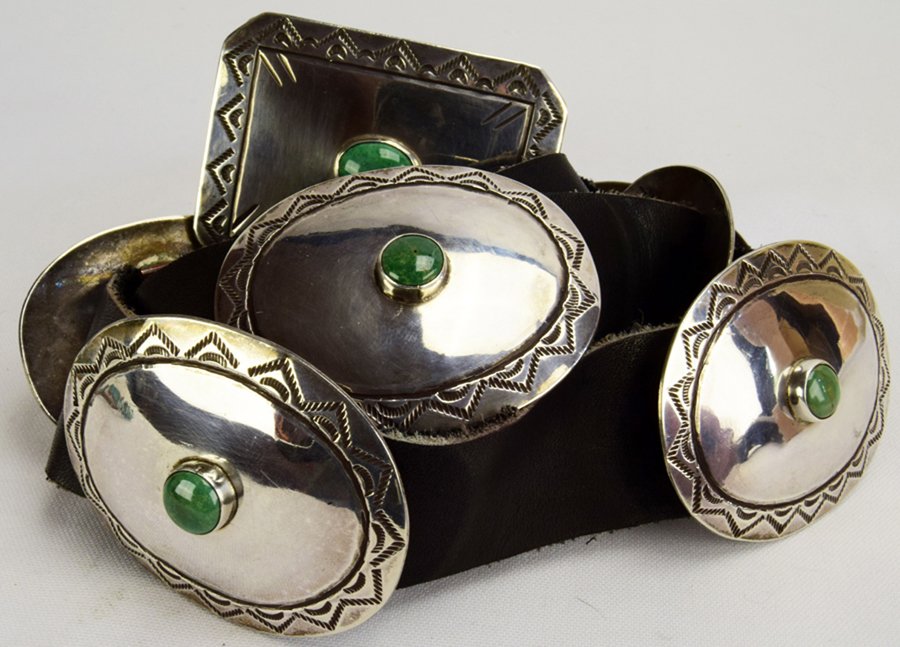 Joe Tortalita Vintage Sterling Concho Belt: Made in the 90's by the late Navajo artist Joe Tortalita this belt measures 42 inches in length with Black Leather that is 1.25 inches wide. The Buckle Measures 2.75 inches wide and is 2 1/8 inches ta