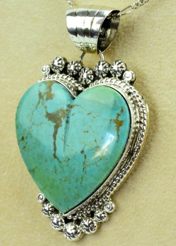 Augustine Largo Kingman Turquoise Heart Pendant: Measures 2 3/8 inches long x 1.5 inches wide. This pendant is done in Kingman Turquoise in a Heart Shape. It is framed with a Rope, Round and Star Bead accent. The back is marked Sterling and Hallmark