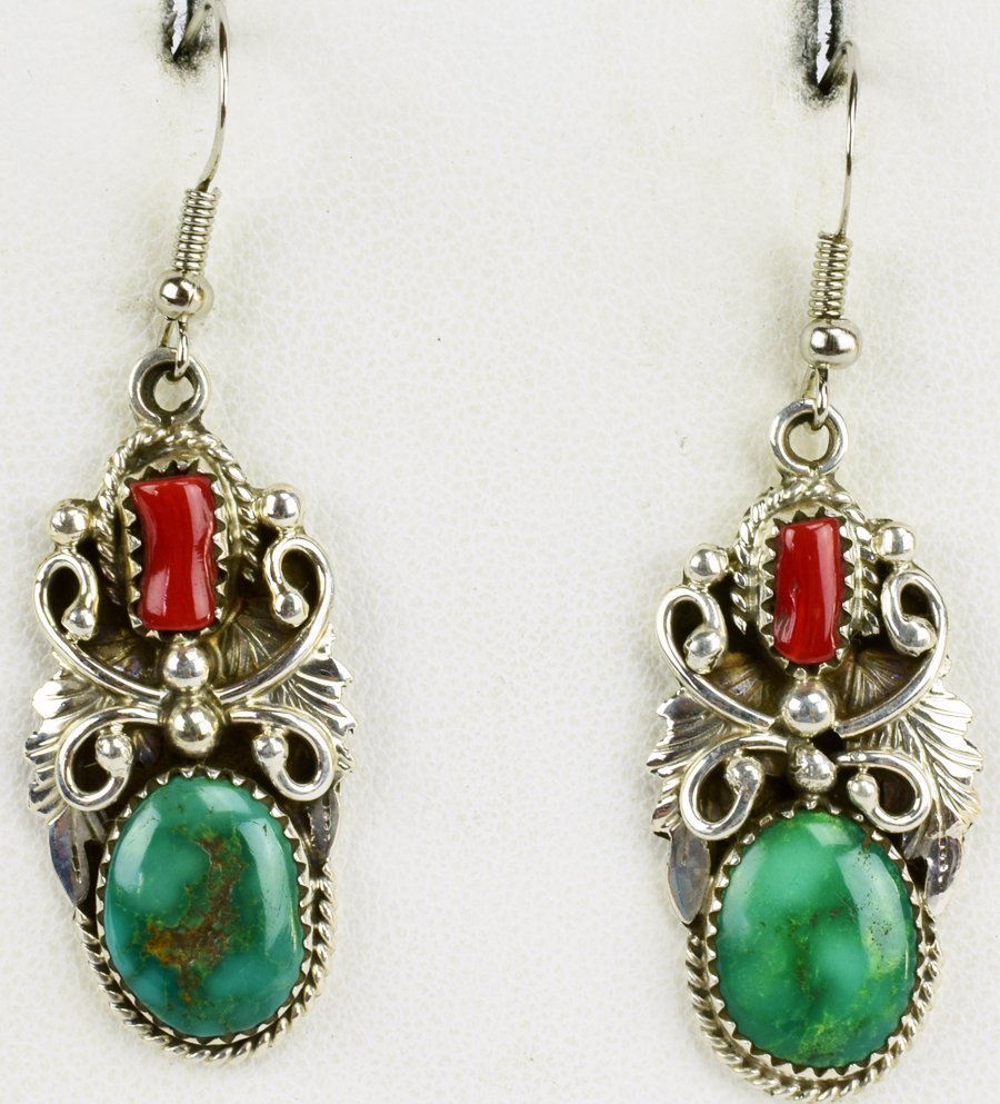 Herbert Begay Sterling Turquoise and Coral Earrings: Measuring 2 inches in length these earrings have a Natural Turquoise and coral stone that is accented with feather, scroll and bead detail. They are marked Sterling and one is signed "H. Begay". Weigh