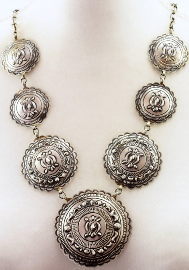 Eugene Charley Sterling Silver Repousse Concho Necklace: Measuring 28.5 inches in length without the Center Concho Medallion drop. This necklace has a Hand made paper clip chain that has a lobster claw closure. The chain portion extends down approx. 7.5 inc