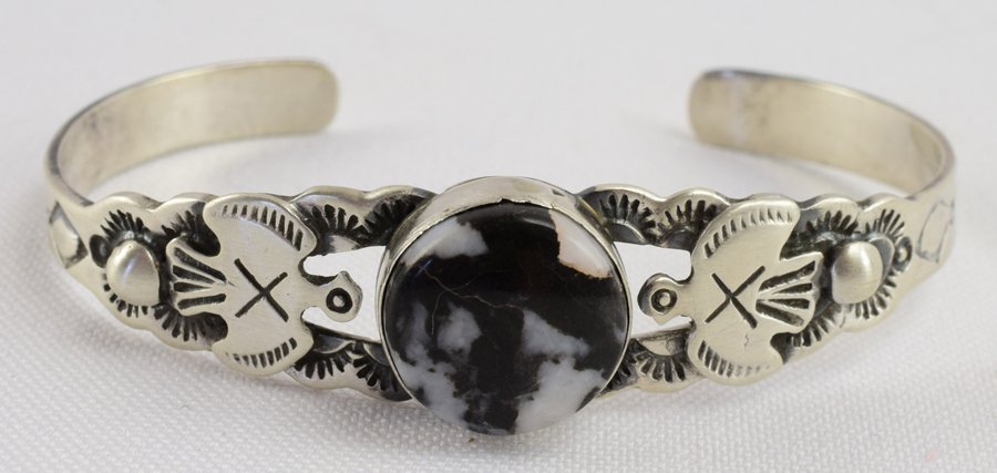 Lorenzo James Sterling White Buffalo Turquoise Bracelet: Measures 1/2 inch wide and has a Natural White Buffalo Turquoise Center Stone accented with a Thunderbird on the sides. Inside measures 5.25 inches plus an opening of 1.25. Stamped Sterling and Signed