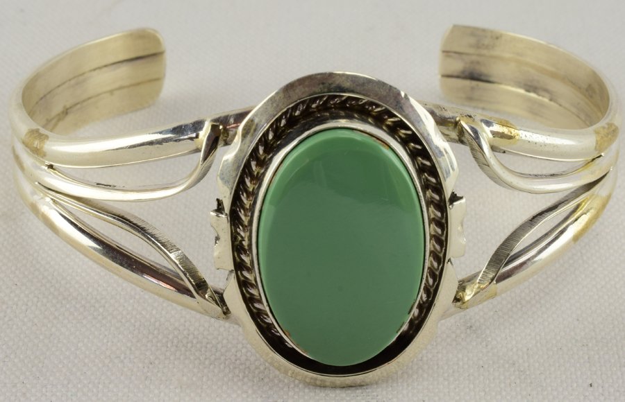 Augustine Largo Sterling Kingman Turquoise Bracelet: Measures 1.25 inches wide. The Center Turquoise stone is a Kingman Turquoise piece which is a beautiful green color. The bracelet has a split band and a shadow box frame with a rope design. Inside mea