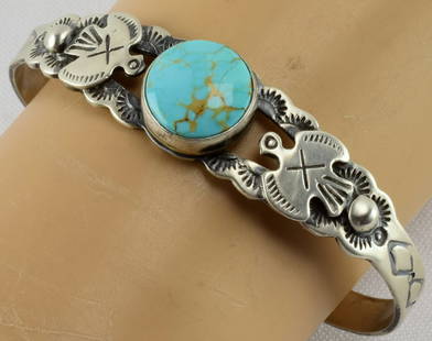 Navajo Sterling Thunderbird Turquoise Bracelet: Measuring 1/2 inch wide in the center with a Natural Turquoise Round stone. This bracelet has the Thunderbird applied to each side along with hand stamped band. Inside measures 5.25 inches plus a gap