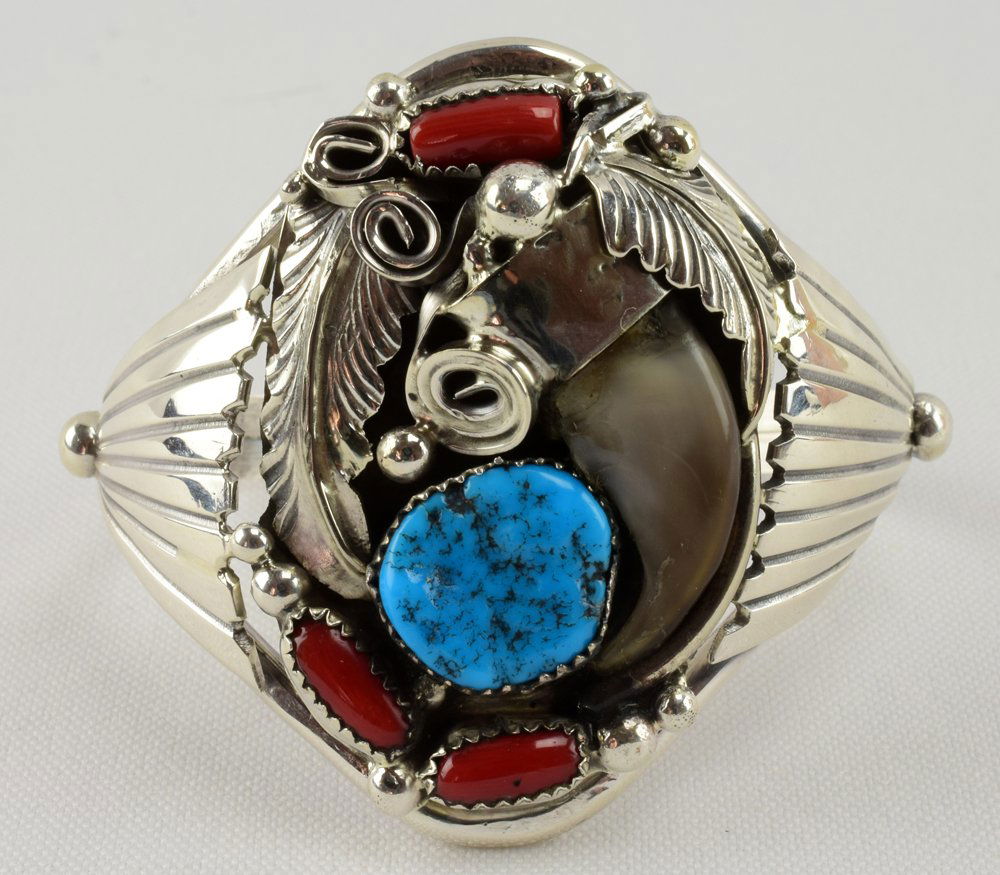 Navajo Bear Claw Men's Cuff with Turquoise & Coral: Measures 2 1/8 inches wide and is accented with a Bear Claw, Natural Turquoise and Coral pieces and a Feather detail. The sides have applied fan or wing designs. Inside measures 5.5 inches plus a gap