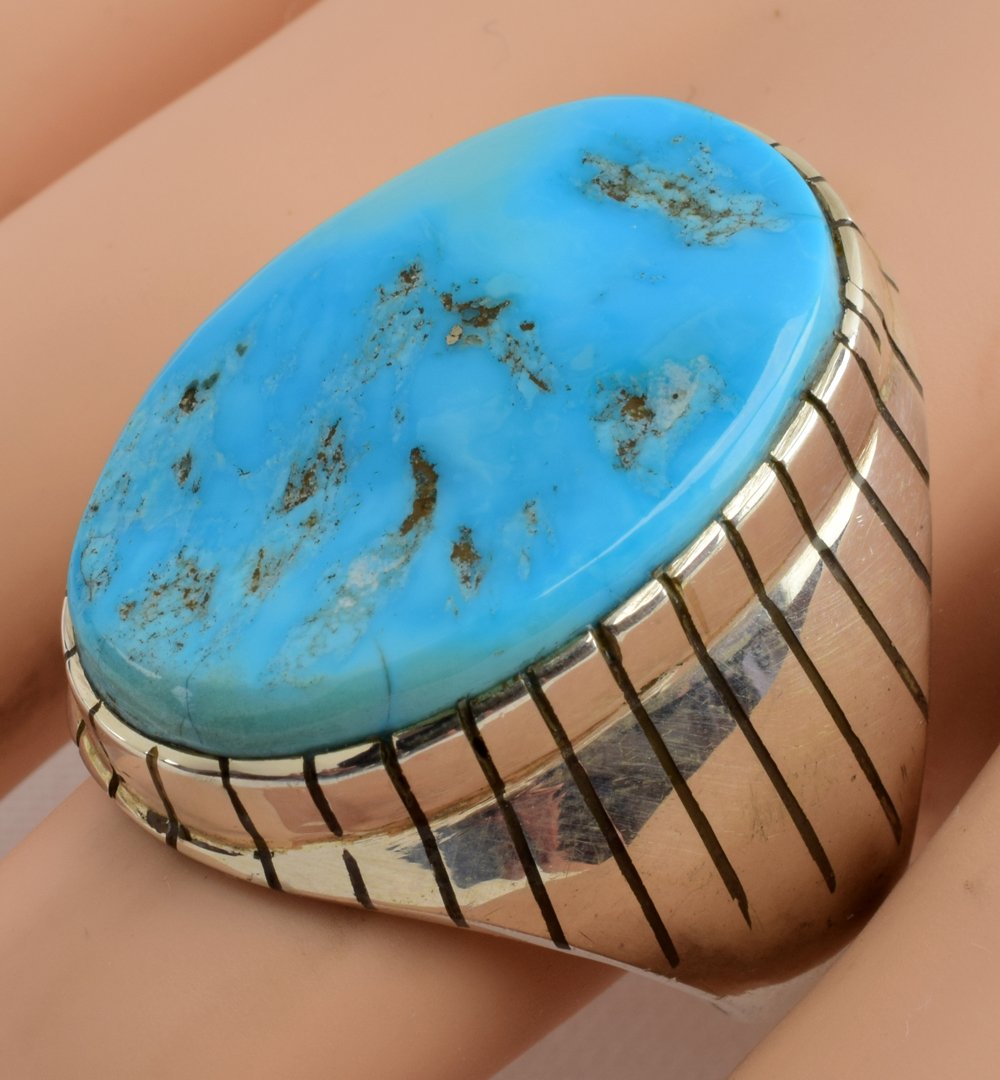 Native American Sterling Sleeping Beauty Men: Measures 1 1/8 inches long with a Natural Sleeping Beauty Turquoise Center stone. The sides have a Sun Ray Pattern. Stamped Sterling and Hallmarked "R" for Ray Jack. Weighs 22.9 Grams and is a Size 11