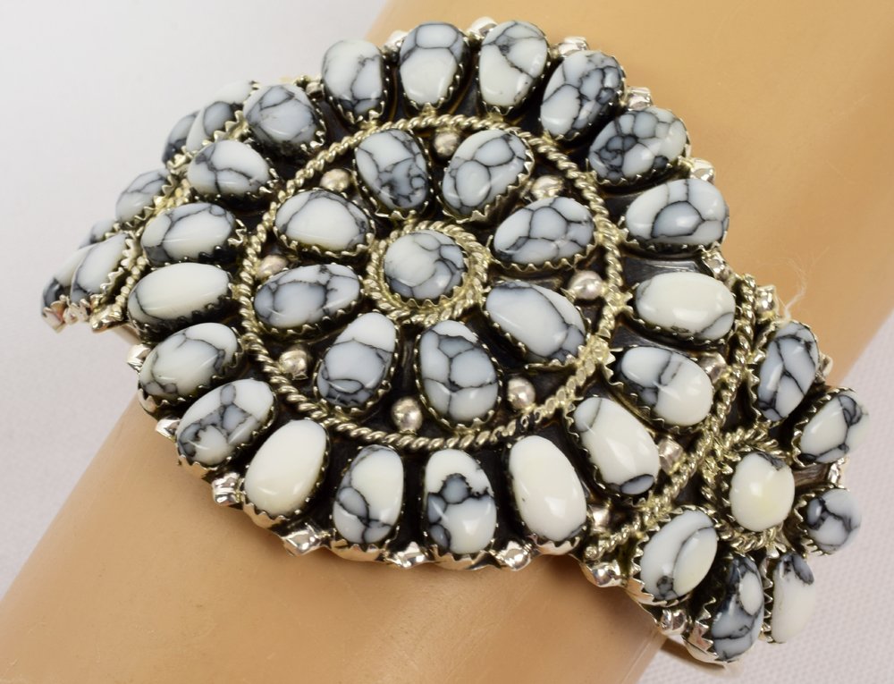 Navajo White Buffalo Turquoise {Howlite} Sterling Cuff: Measures 2 inches wide with White Buffalo Turquoise {Howlite} stones done in a cluster design. The inside measures 5.25 inches with a gap of 1.25 inches. Marked Sterling and Hallmarked "JW". Weighs 13