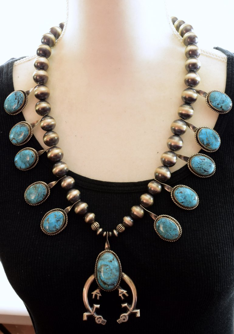 Navajo Kingman Squash Blossom Necklace w/Navajo Pearls: When we got this item we were talking to the artist and he indicated that the symbol below the turquoise drop was Mother Earth and Father Sky. This necklace measures 26 inches in length {without the p
