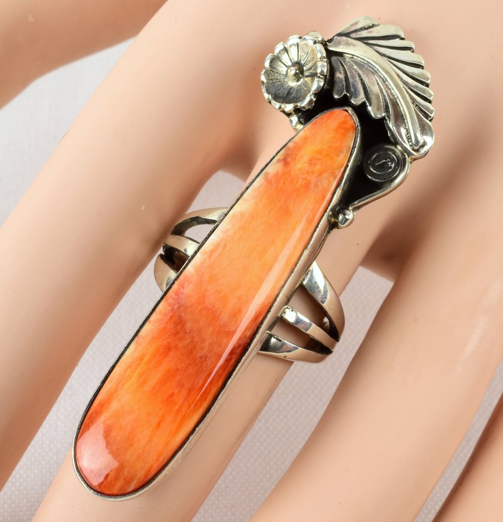 Russell Sam Sterling Silver Spiny Oyster Long Ring: Measures 2.5 inches long with a Polished Spiny Oyster center stone accented with Feather and Cactus Flower detail. Sterling Silver Signed "Russell Sam". Weighs 15.5 Grams and is a Size 8.25. Native Am