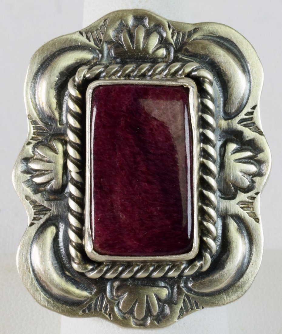 Jeff James, Jr. Purple Spiny Oyster Repousse Ring: Measures 1.5 inches long x 1.25 inches wide. This ring has a Natural Purple Spiny Oyster center stone accented with a satin finish Repousse frame. Stamped Sterling and Hallmarked "JJJ". Weighs 15.6 Gr
