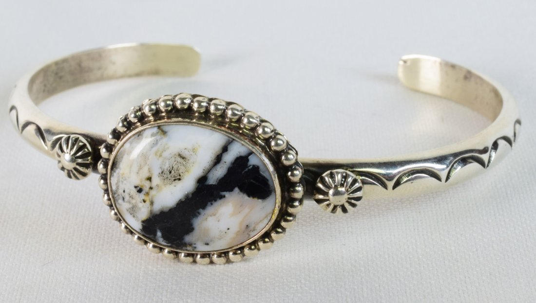 Native American White Buffalo Turquoise Cuff: Measuring 3/4 inch wide with a Natural White Buffalo Turquoise stone that is accented with a bead frame. The band is stamped and has star concho pieces. Inside measures 5.5 inches plus a gap of 1 inch