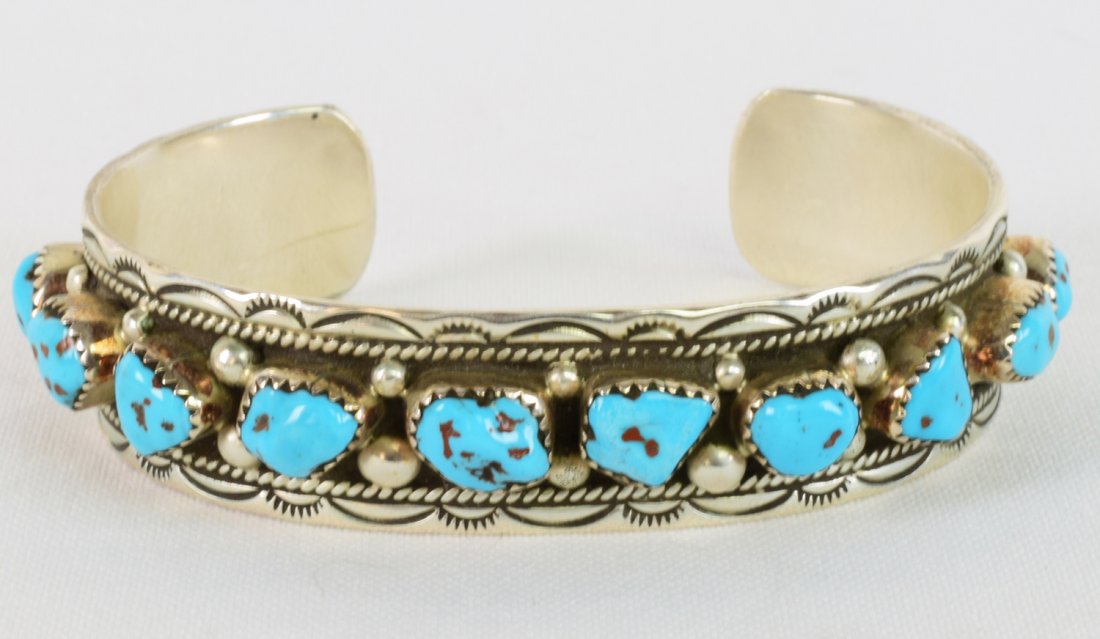 Navajo Sterling Silver Kingman Turquoise Bracelet: Measuring 1/2 inch wide this bracelet is done with Natural Kingman Turquoise nuggets across the top. Each piece is bezel set with a rain drop bead. Inside measures 5.75 inches plus a gap of 1.25 inche
