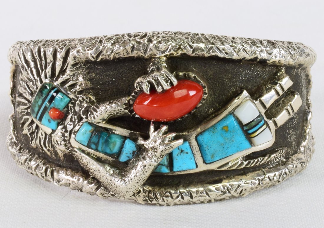 Lester James Sterling Tufa Cast Kachina Inlay Bracelet: Measures 1 3/8 inches wide and done in the Tufa Cast style. This artist is known for his Award Winning Tufa and Inlay work. This bracelet has hand inlay of Turquoise, Jet, Mother of Pearl and Coral ac