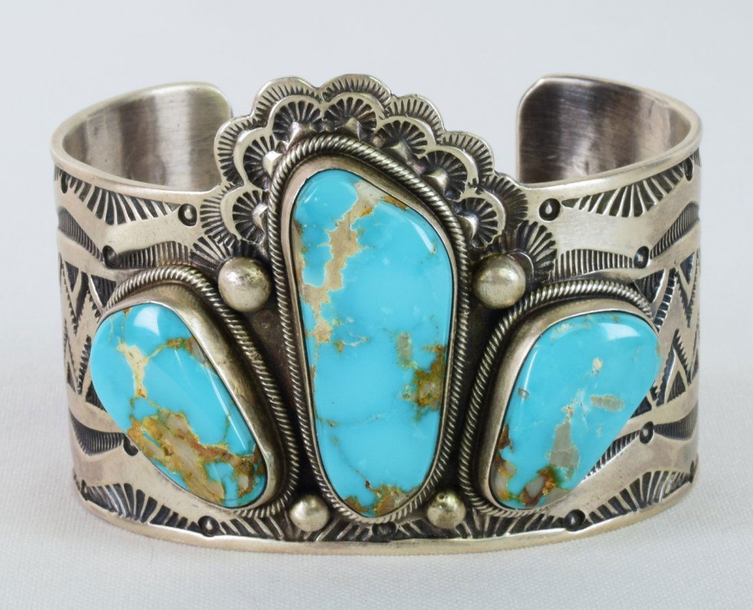 D. Livingston Sterling Morenci Turquoise Bracelet: Measuring 2 inches wide this piece is made a bit different than most 3 stone cuffs. The artist used the Center Turquoise stone to sit above the side pieces and gave it sort of a "Headdress" look by ad