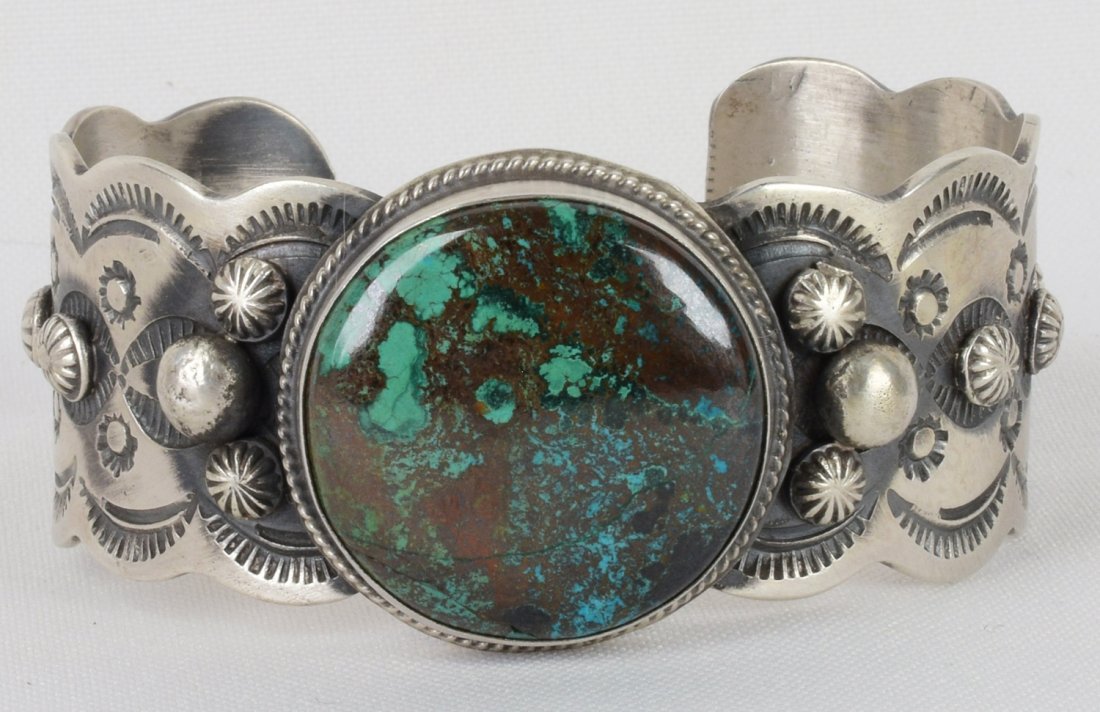 Native American Sterling Red Mtn. Turquoise Bracelet: Measures 1.25 inches wide this piece has a round Natural Turquoise Center Stone. The stone has a wonderful deep blue green color and the band is accented with star concho and bead design. Inside measu