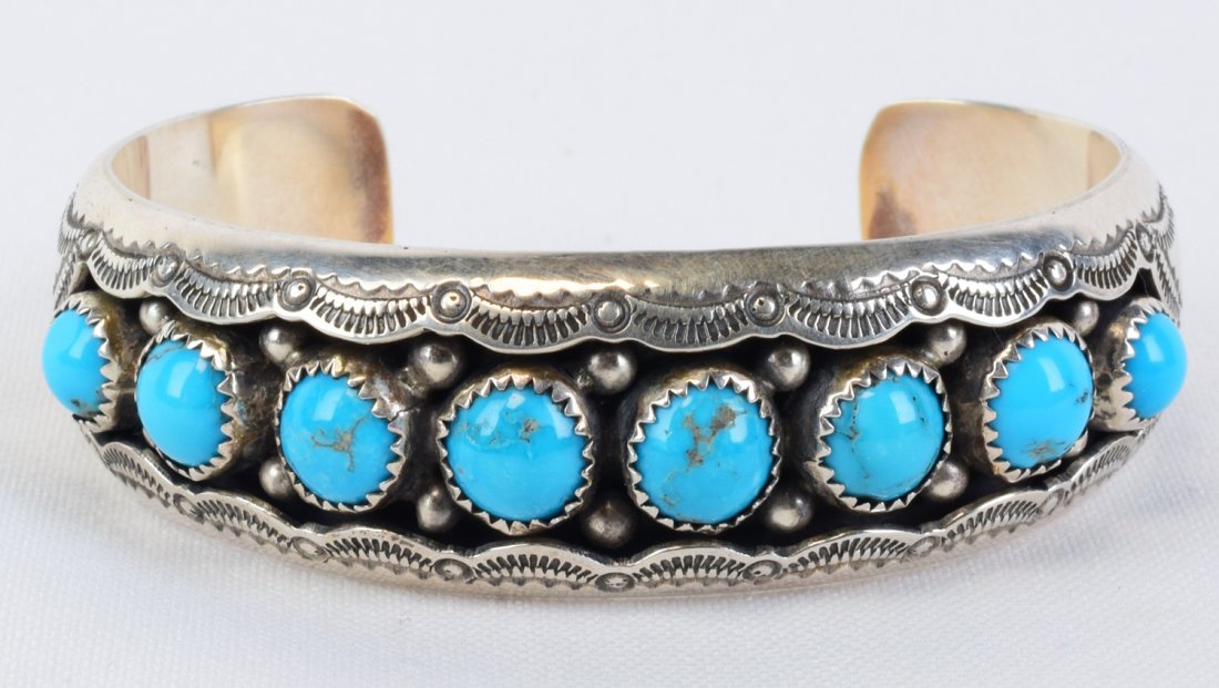 Navajo Sterling Sleeping Beauty Turquoise Cuff: Measures 3/4 inch wide with 8 Bezel Set Natural Sleeping Beauty Turquoise stones across the top. The stones have been place in a shadowbox style and have bead and stamp design work surrounding. Inside