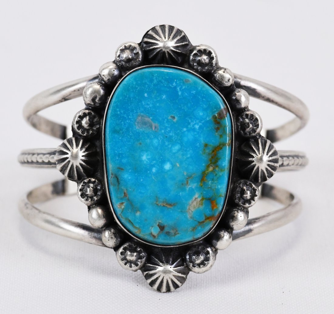 Native American Sterling Blue Ridge Turquoise Cuff: Measures 2 inches wide with a Natural Blue Ridge Turquoise center stone that is accented with Star Concho and bead design. Inside measures 5 inches plus a gap of 1.5 inches. Sterling Silver, Hallmarke