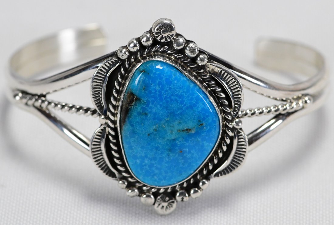 A. Toadlena Sterling Blue Ridge Turquoise Bracelet: Measures 1.5 inches wide with a Natural Blue Ridge Turquoise center stone. The stone is accented with a rope and bead frame. Inside measures 5 1/8 inches plus a gap of 1 1/8 inches. Stamped Sterling/S