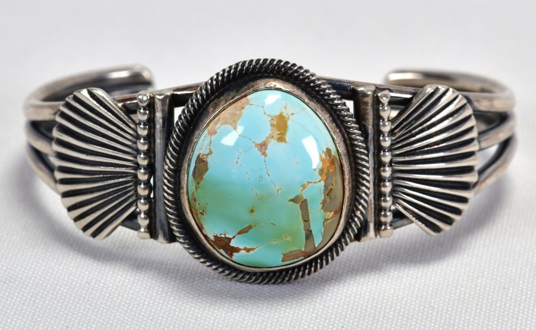 Leon Martinez Sterling Carico Lake Turquoise Cuff: Measures 1.25 inches wide. This piece is well made with a beautiful Center stone from the Carico Lake Turquoise mine. It has detailed applied sterling on the sides. Inside measures 5.25 inches plus a 