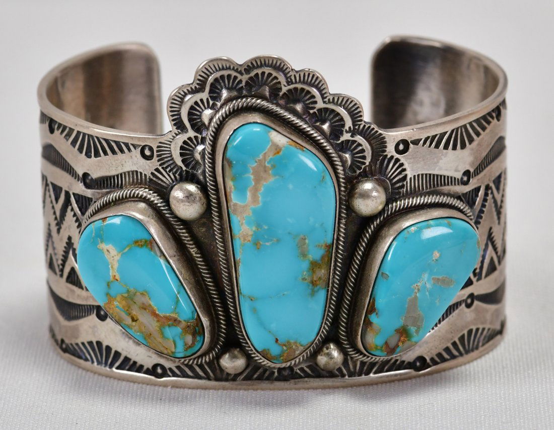 D. Livingston Sterling Morenci Turquoise Bracelet: Measuring 2 inches wide this piece is made a bit different than most 3 stone cuffs. The artist used the Center Turquoise stone to sit above the side pieces and gave it sort of a "Headdress" look by ad