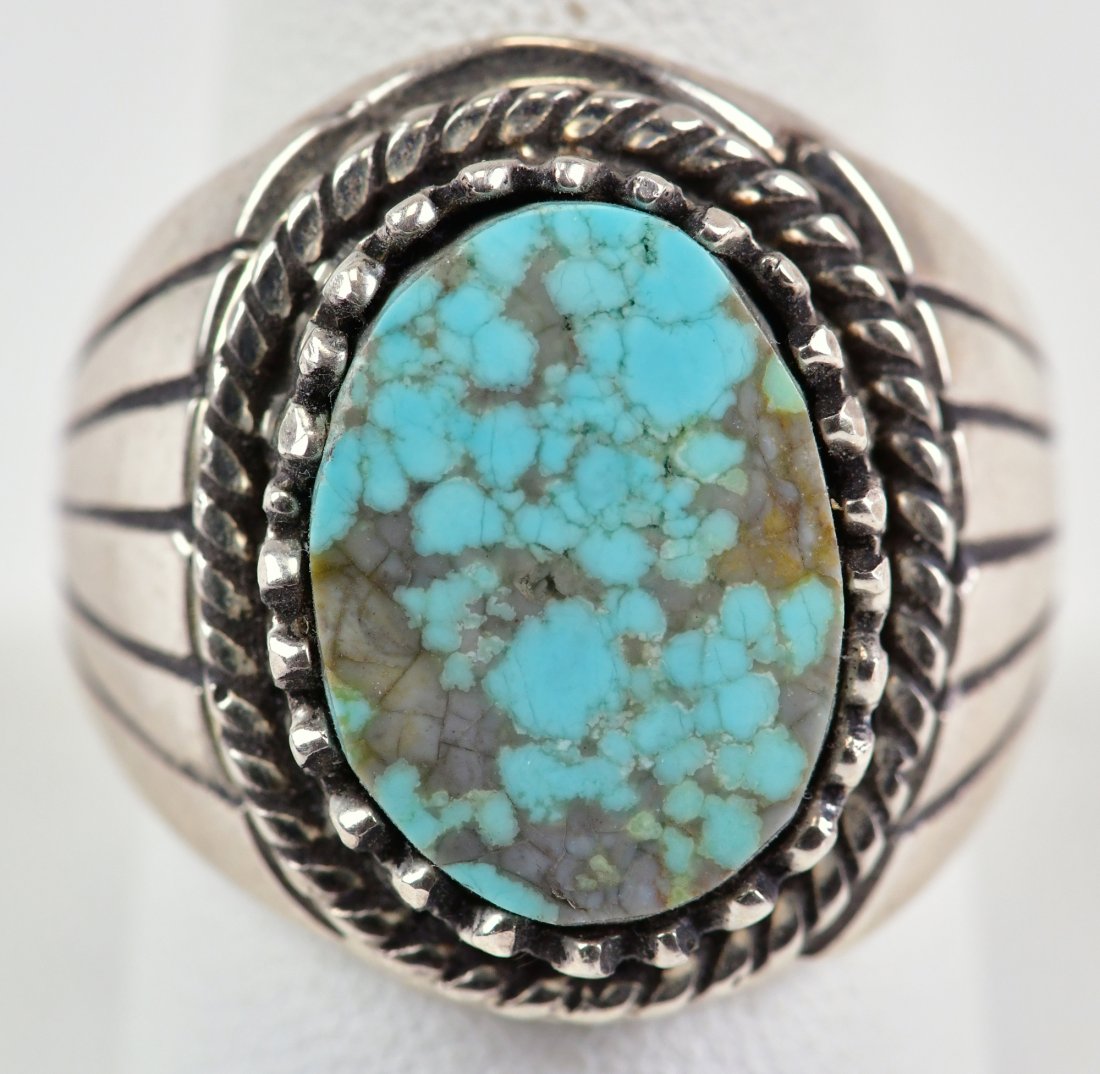 Navajo Sterling Sierra Nevada Turquoise Men's Ring: Measures 1 inch in length and has a Saw Tooth Bezel holding the Natural Turquoise Center stone. The sides have a Sun Ray pattern. Sterling/Hallmarked "CJ"/Weighs 21.1 Grams and is a Size 9.5. Native A