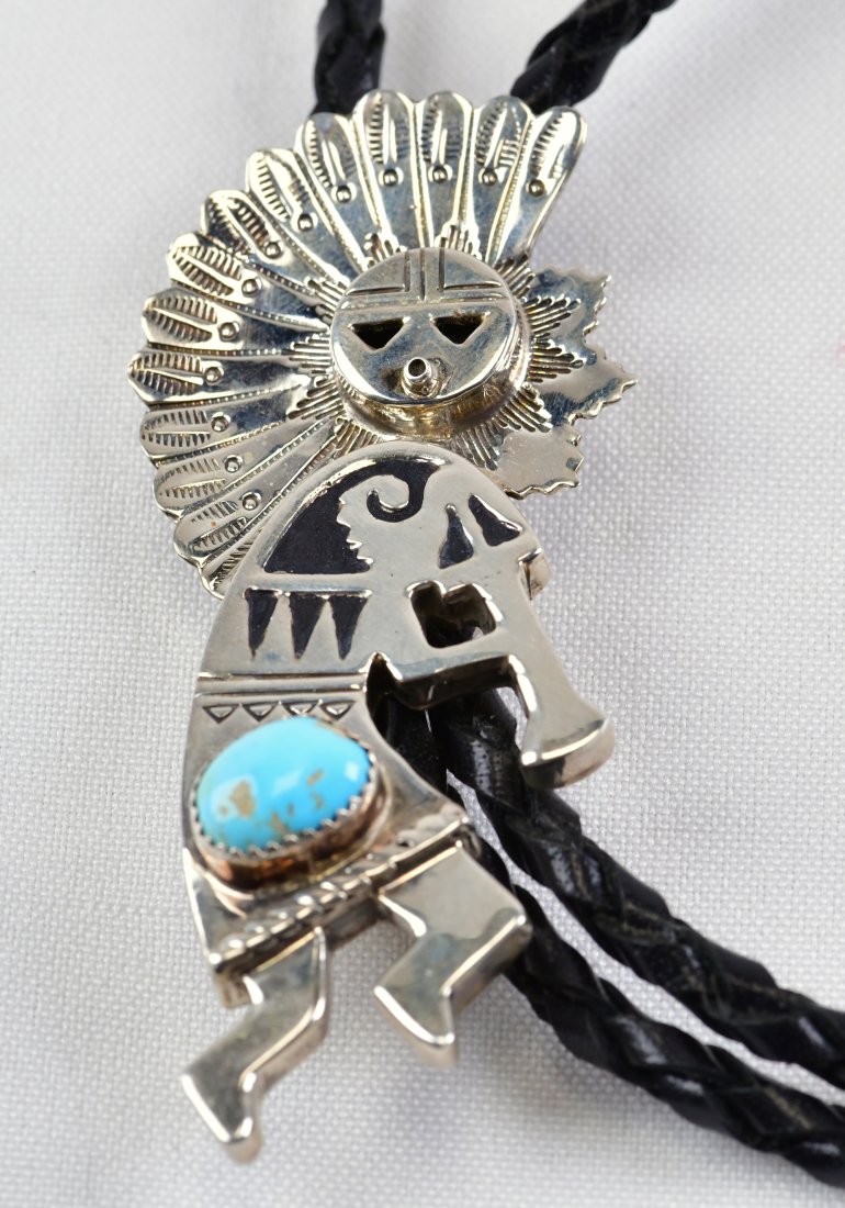 Alonzo Mariano Sterling Kokopelli Bolo Tie: Leather measures approx. 38 inches in length with Sterling Silver End Cones. The Slide is done in a Kachina/Kokopelli Style with a Kachina Headdress and a Kokopelli Body. The piece is done in an Overl