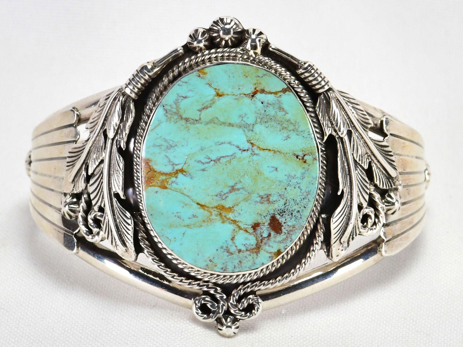 J. Delgarito Sterling Silver Nevada Green Turquoise Bracelet: Sterling Silver| J. Delgarito Sterling Silver Nevada Green Turquoise Bracelet w/Feather detail| Genuine Nevada Green Turquoise| Inside measures 5.5" plus a gap of 1.25" - Total 6.75"| Face Width 2"| H