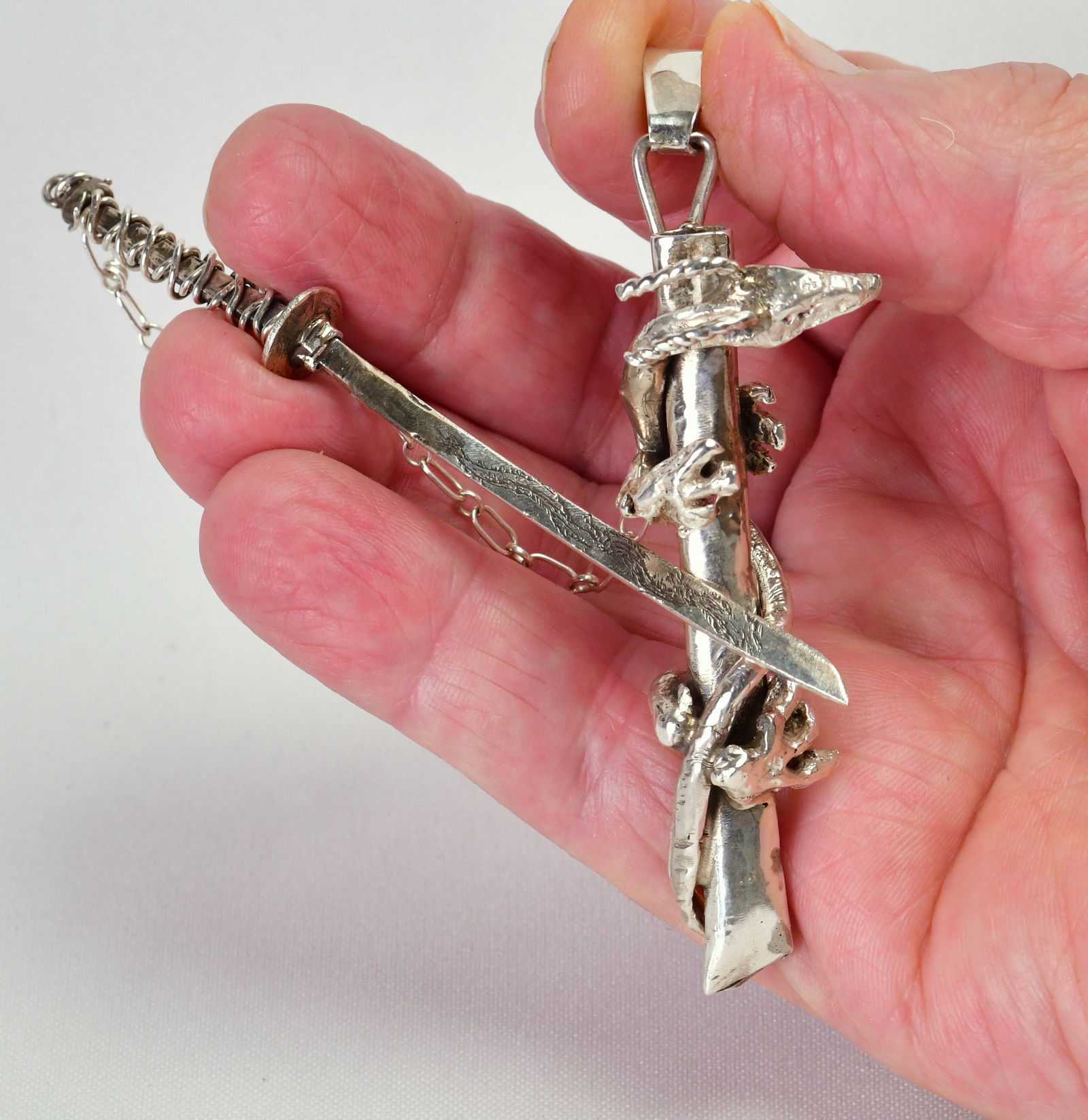 Zuni Don Dewa -Sterling -Very Unique Dragon/Sword Pendant: Sterling -Very Unique Dragon/Sword Pendant.Unique indeed. Depicting The Dragon and the Sword that will Slay Him.Measuring 4-1/2" in length with the sword in the sheath.One of Don Dewa's Darker creatio