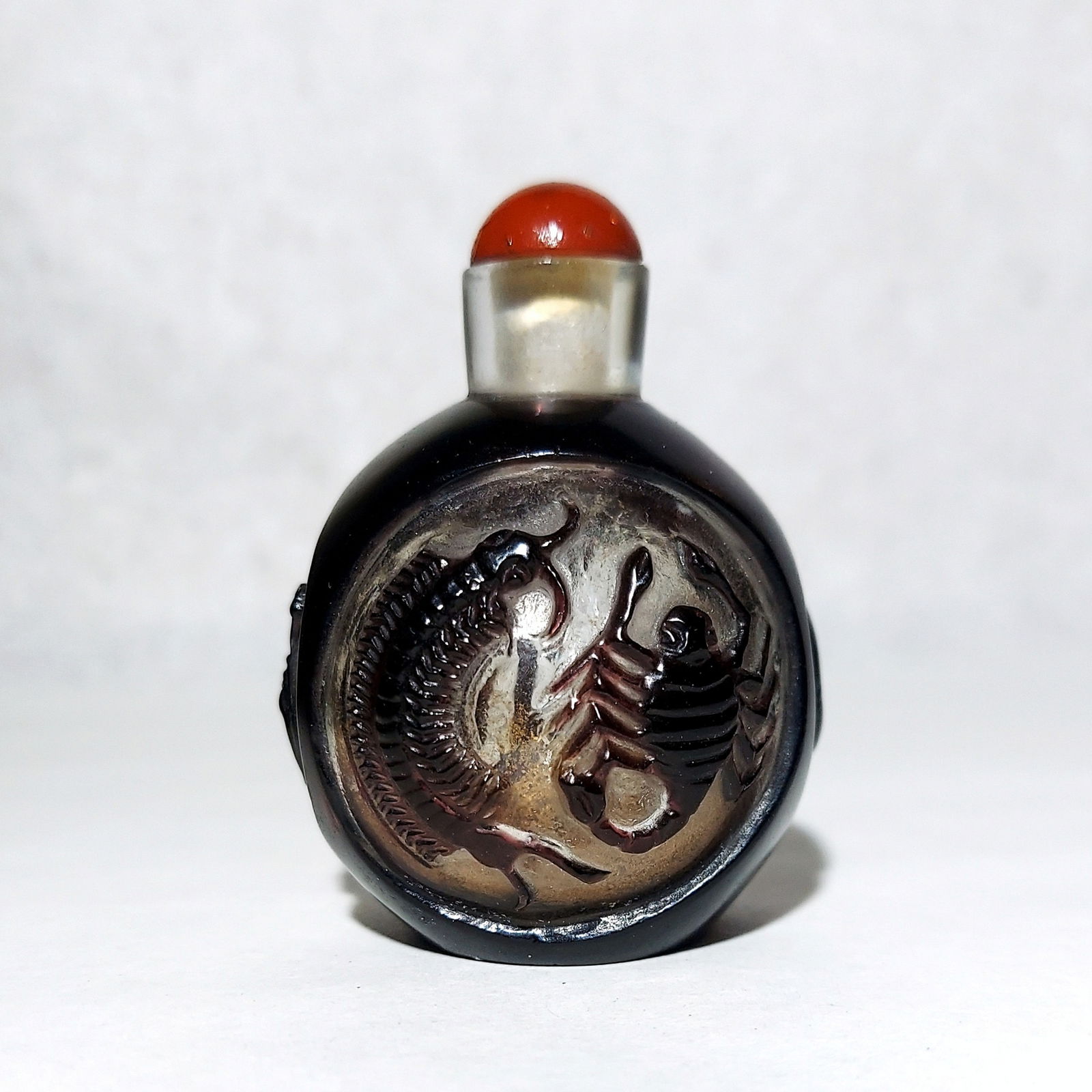 Chinese Peking Overlay Glass Snuff Bottle with a Coral Stopper.: Chinese Peking Overlay Glass Snuff Bottle with a Coral Stopper. Late Qing dynasty the triangular bottle with round bottom features carved designs, depicting chilong and other mythological creatures. D