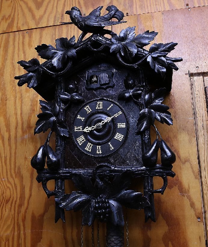 Carved Cuckoo Clock: Large and elaborately carved case with foliate, fruit and bird carvings. Age: Circa 1920 to 1940 Condition: Good: Complete with pendulum and two pinecone form weights. Dark even patina with minor chip