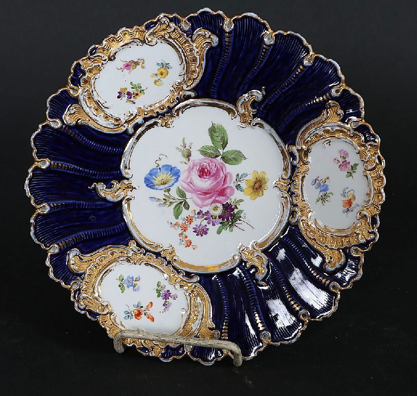 Meissen Scalloped Dish: Shell edged cobalt porcelain dish having floral hand painted central medallion and cartouche edge medallions bearing the blue under glaze cross sword mark. Age: Late 19th/Early 20th Century Condition: