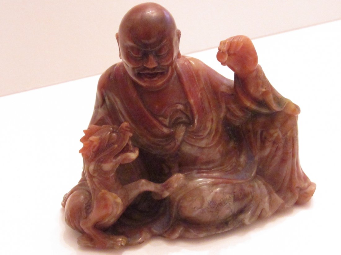 Chinese Carved Red Steatite Luohan Taming Dragon: Red colored soapstone man with dragon and pearl. 4 1/2 inches long by 3 3/4 inches tall by 2 1/8 inches deep.This lot depicts either the Taming Dragon Luohan (降龍羅漢 Xianglon