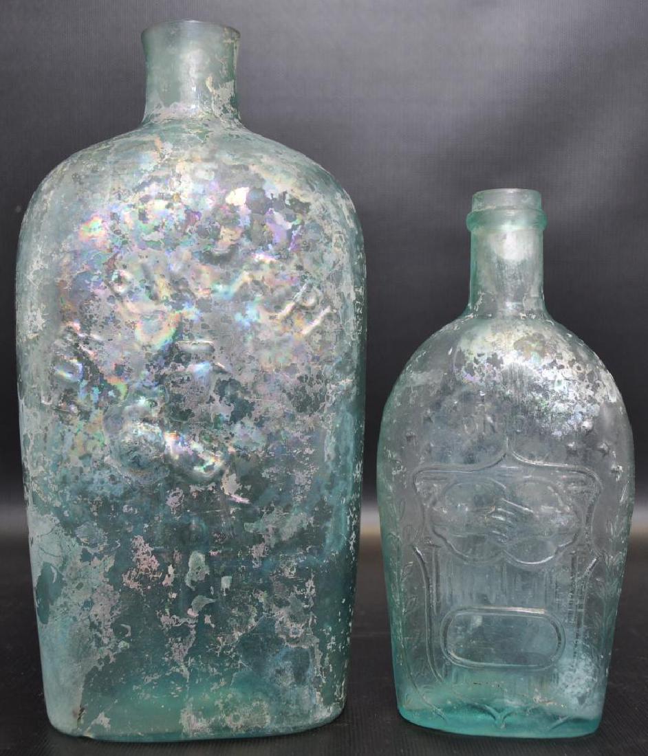 Group of 2 : Antique Glass Whiskey Flasks: Larger 8 1/2 x 4 1/2 x 2 1/2 inch aquamarine flask has the raised image of a miner beneath "For Pike's Peak". Opposite side shows a hunter and his dog. Smaller 6 1/2 x 3 x 1 1/2 aquamarine flask with