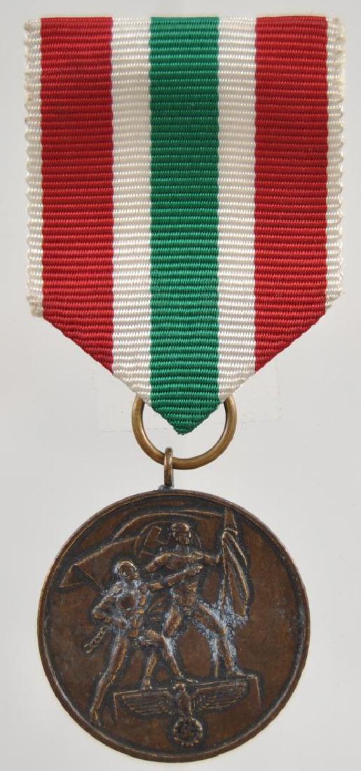 WW2 German March 1939 Memel Lands Decoration.: Measures 1 1/4" in diameter. The front shows two men holding flags with a German eagle at the base. The reverse side reads Zur Erinn Erung An Die Heim Kehr Des Memellandes 22 Marz 1939 . Includes the