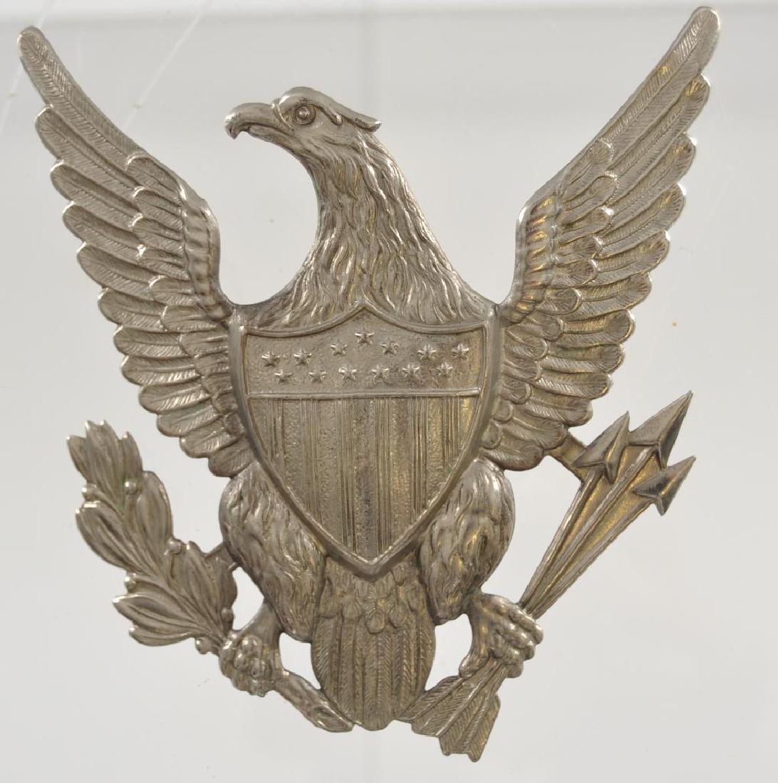 US Indian Wars Army Military Eagle Spike Helmet: Measures 4 wide by 4 1/4 tall. The front shows an American eagle with a shield in the center of his chest. He is holding oak leaves and three arrows in both talons. Has a screw mount post and brass nu