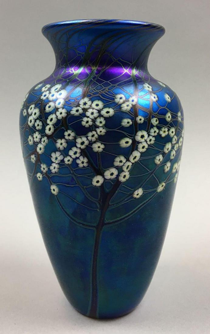 Orient and Flume Iridescent Blue Vase: This art glass vase by Orient & Flume is 6-1/2 inches tall; hosts a deep iridescent blue, and features a stylized image of a blossoming hawthorn tree along the side. Beautifully vibrant, the vase is i