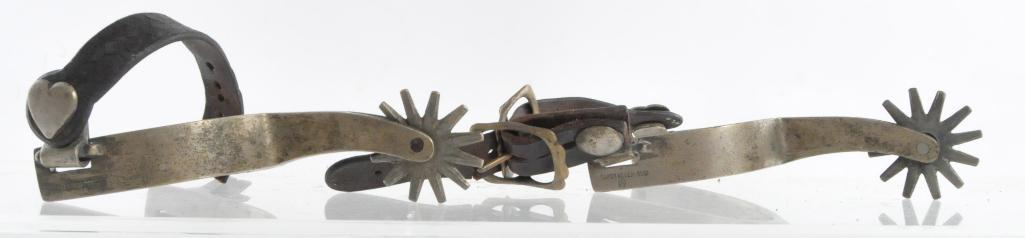 Antique Western Cowboy Buerman Spurs: Super Never Rust with Buerman "B" on the outside heel, Heel Width 3 inches, Total Measurement 4 x 6 1/2 x 2 inches. Special Heart Button Design. Damaged Leather Strap
