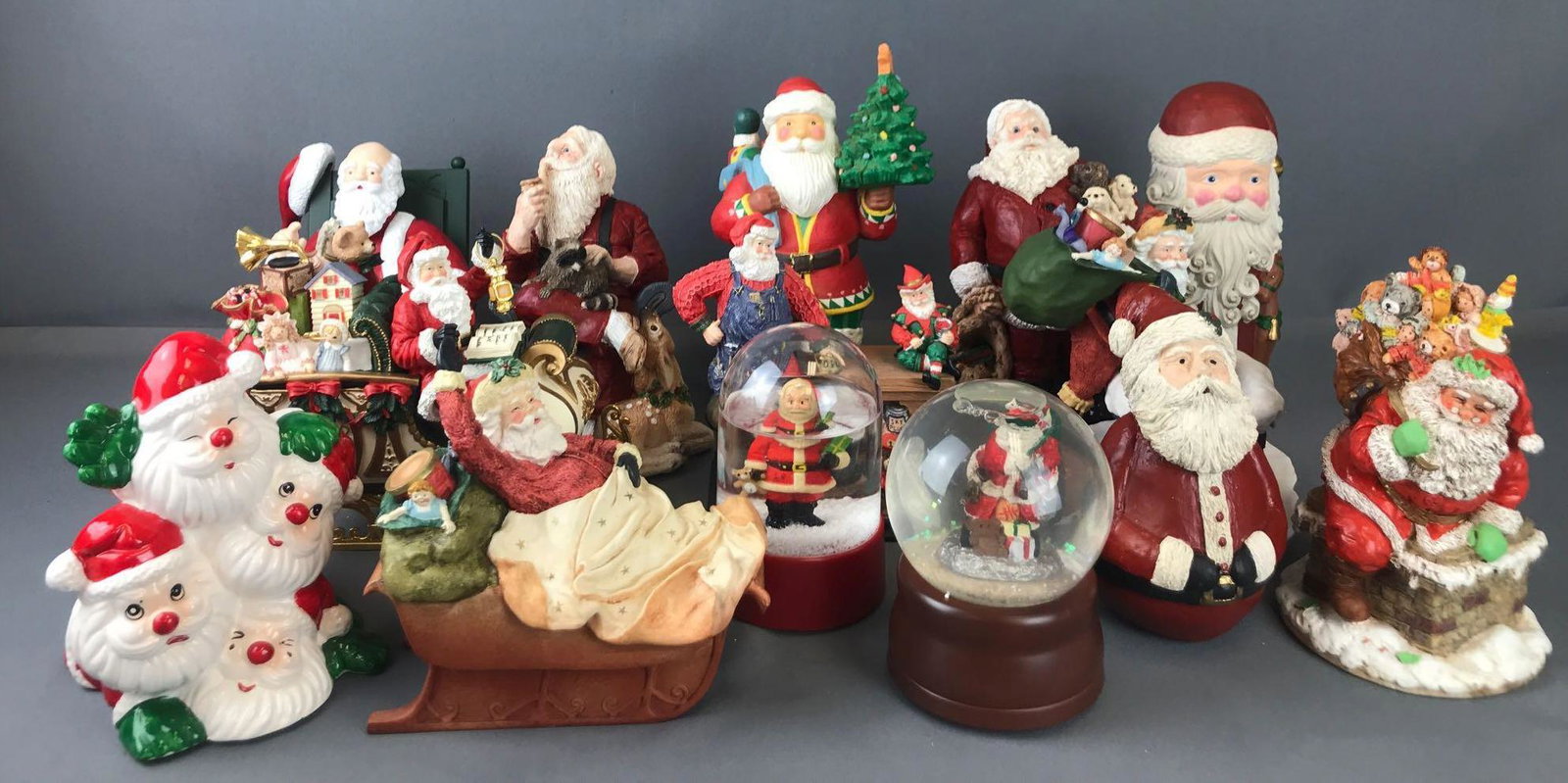 Group of 14 Santa figurines and more: Musical snow globes, coin bank. Largest is 10.5 inches